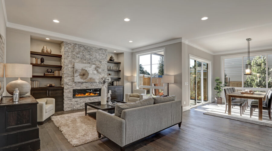 Living room interior in gray and brown colors features gray sofa atop dark hardwood floors facing stone fireplace with built-in shelves. Northwest, USA